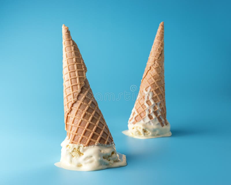 Two melted ice cream with ice cream cones on pastel blue background. Minimal summer food concept