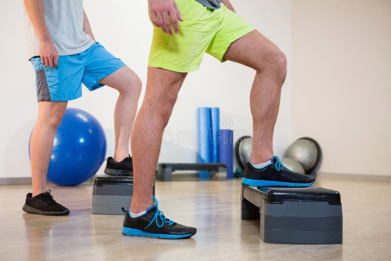 Two Men Doing Step Aerobic Exercise with Dumbbell on Stepper Stock