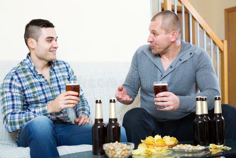 Two men drinking beer stock photo. Image of indoor, home 74595332