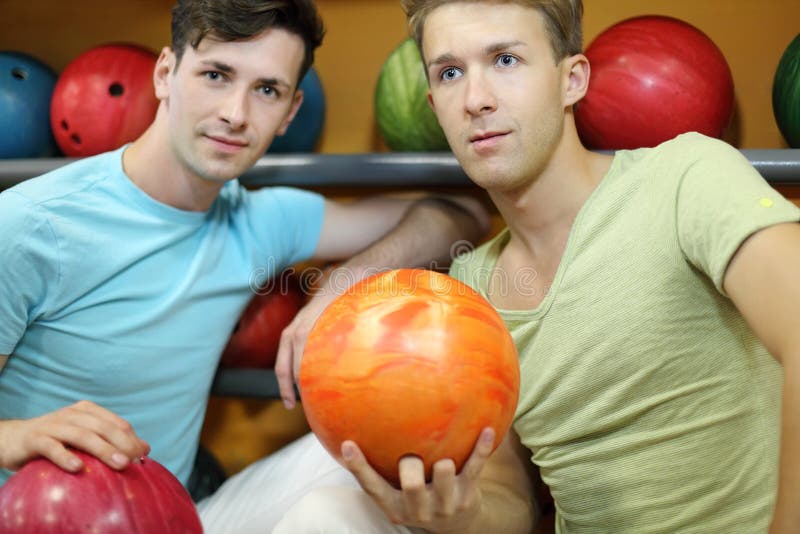 Two Men Sit Near Shelves With Balls And Hold Balls Stock Image Image