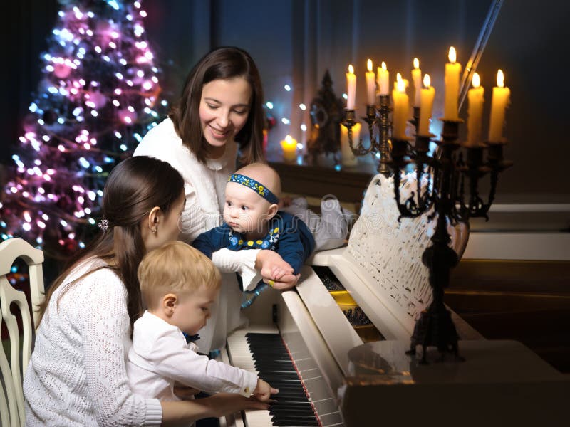 Two mothers with children in the New Year at a white grand piano royalty free stock photos Two mothers with children in the New Year at a white grand piano royalty free stock photos