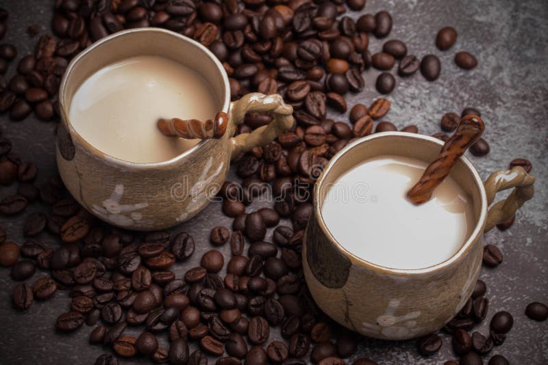 Two Mugs of Coffee with Coffee Beans on a Dark Backdrop Stock Photo