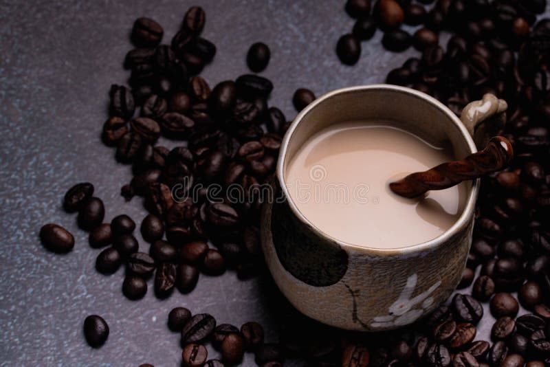 Two Mugs of Coffee with Coffee Beans on a Dark Backdrop Stock Photo