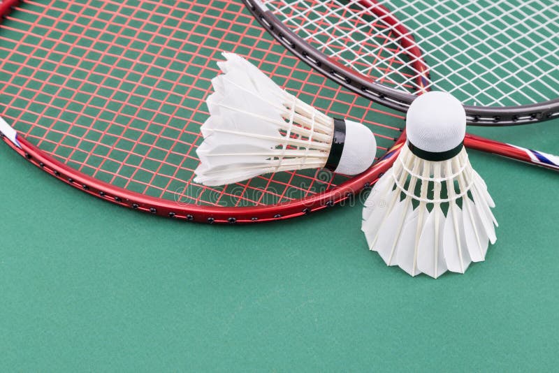 Two new badminton shuttlecock with rackets on green mat court. Two new badminton shuttlecock and rackets on green mat PVC court stock photo Two new badminton shuttlecock with rackets on green mat court. Two new badminton shuttlecock and rackets on green mat PVC court stock photo