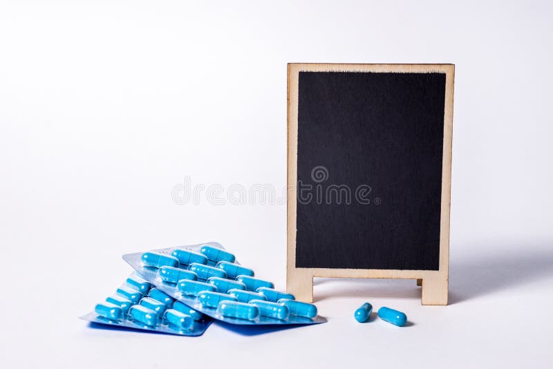 Two packages of blue capsules and a chalkboard mock up with space for text. Pills for men`s health and sexual energy. Concept of erection, potency. Treatment of male infertility. Copy space