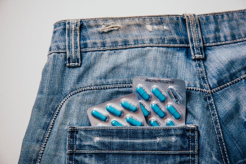 Two packages of blue capsules in the pocket of his pants.Pills for men`s health and sexual energy in jeans. Concept of erection, potency. Treatment of male infertility, impotence and prostatitis