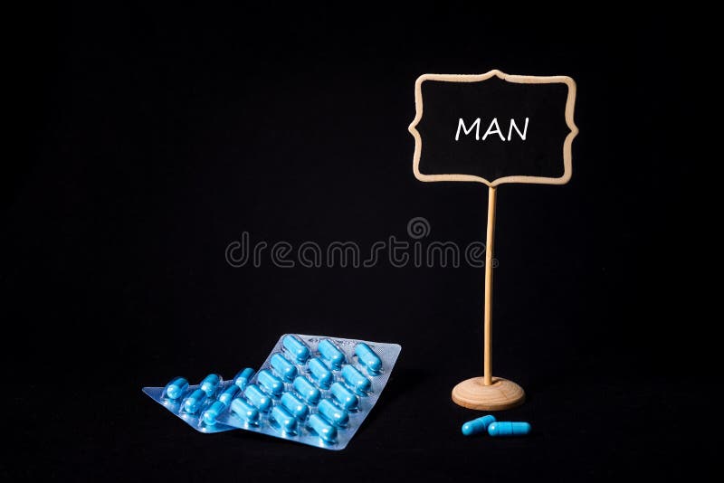 Two packs of blue capsules and the word man on a chalkboard. Pills for men`s health and sexual energy. Concept of erection, potency. Treatment of male infertility and impotence and prostatitis