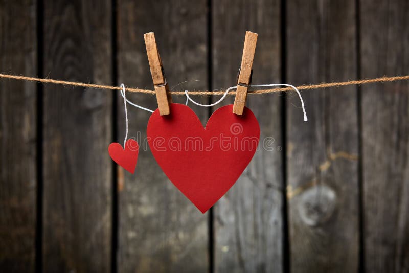 Two lovely red hearts - big and small hanging on the clothesline. On old wood background. Two lovely red hearts - big and small hanging on the clothesline. On old wood background.