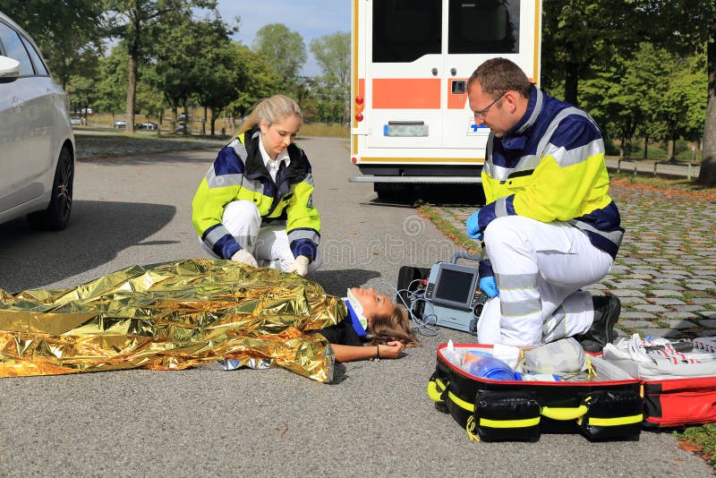Two paramedics helping a woman after a traffic accident with golden blanket stock photos Two paramedics helping a woman after a traffic accident with golden blanket stock photos