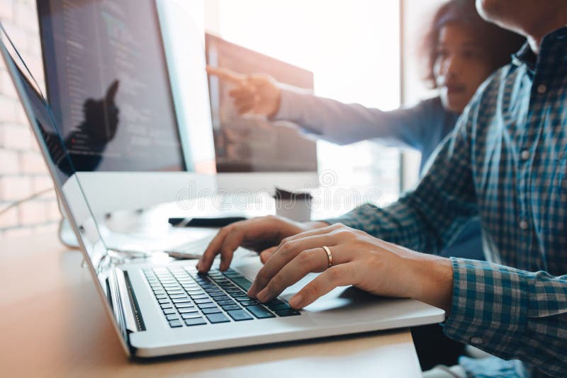 Two partnerships developing programming and coding technologies working on laptop and analyzing together stock image