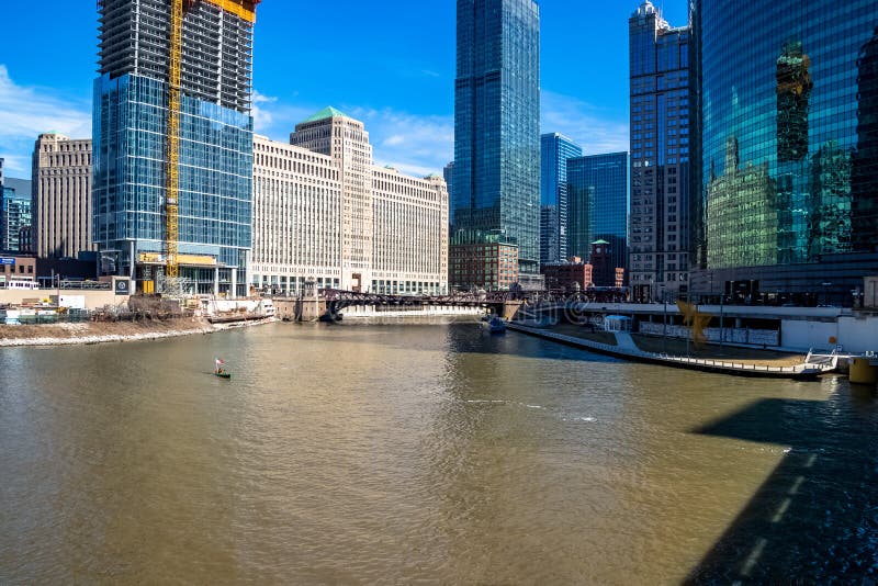 Two people ride the Chicago River in an Irish American themed canoe, with Chicago skyline and construction of skyscrapers in royalty free stock image Two people ride the Chicago River in an Irish American themed canoe, with Chicago skyline and construction of skyscrapers in royalty free stock image