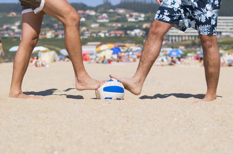 Two people stepping a ball on the beach royalty free stock images