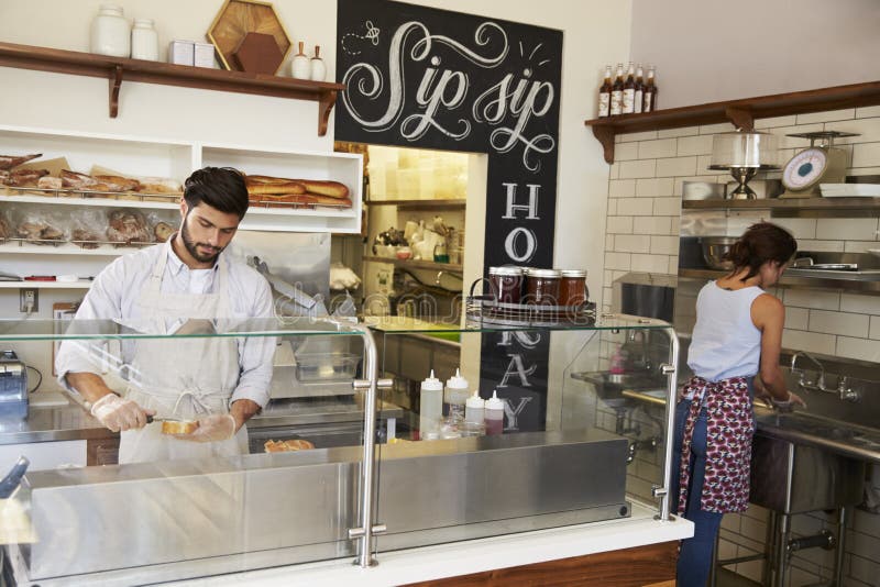 Two people working behind the counter at a sandwich bar royalty free stock photo