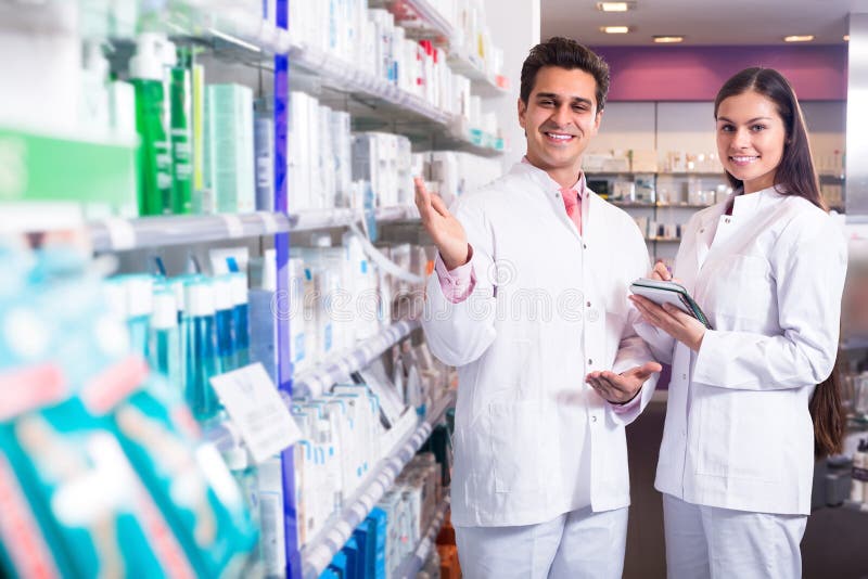 Portrait of two smiling pharmacists working in modern pharmacy. Portrait of two smiling pharmacists working in modern pharmacy.