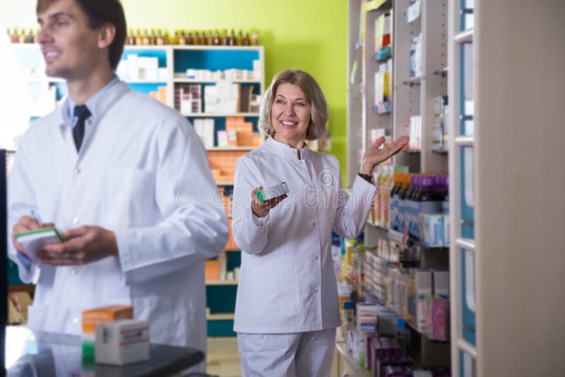 Smiling pharmacist and pharmacy technician posing in drugstore. Smiling pharmacist and pharmacy technician posing in drugstore