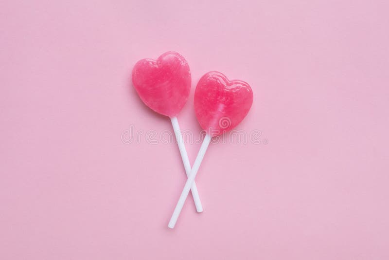 Two Pink Valentine`s day heart shape lollipop candy on empty pastel pink paper background. Love Concept. top view. Minimalism colorful hipster style.