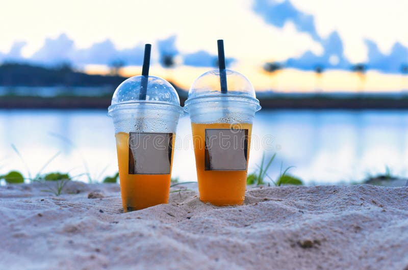 Two Plastic Cups with Iced Tea Take Away Against Sea Stock Photo