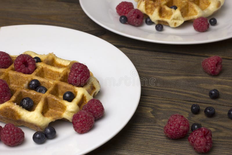 Two plates of waffles with berries on the table stock photo