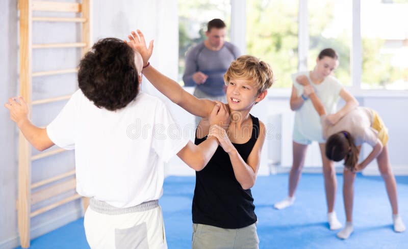 Two preteen boys doing a head kick during self defense training