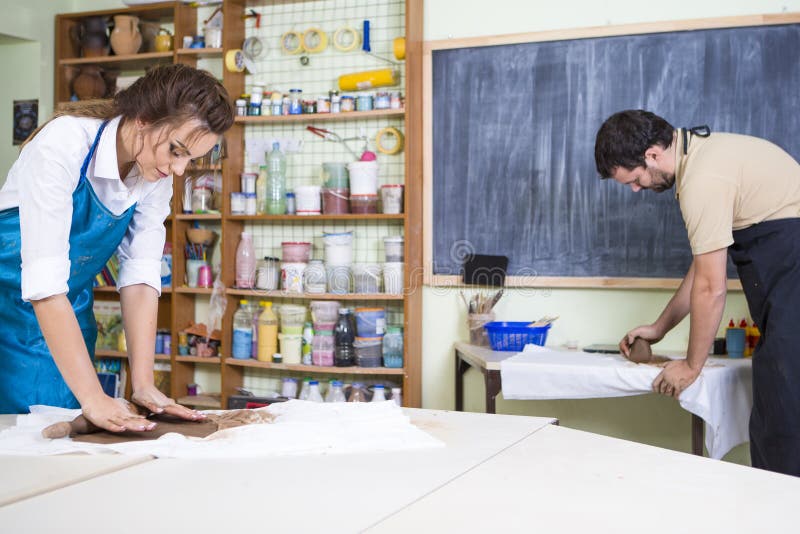 Two Professional Clay Makers During a Process of Clay Preparation on Tables in Workshop royalty free stock image