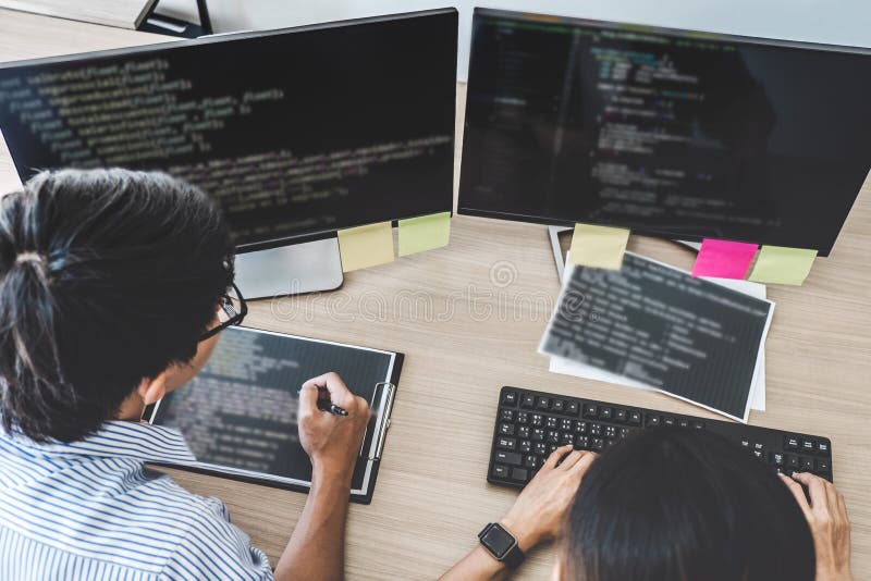 Two professional programmers cooperating at Developing programming and website working in a software develop company office, writing codes and typing data code. Developing programmer stock images, royalty-free photos and pictures