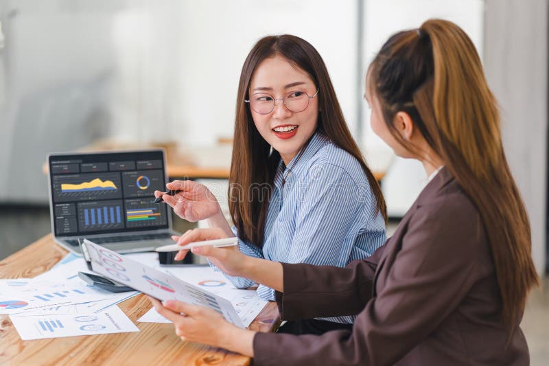 Two professionals analyzing business data on dashboard screen and discussing financial graphs and charts in a modern royalty free stock photo