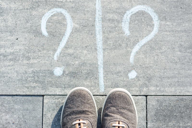 Two question marks handwritten on an asphalt road with sneakers stock photo