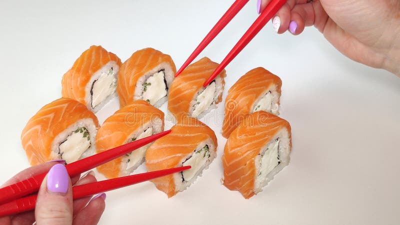 Two Red Hands With Chopsticks Taking Sushi.