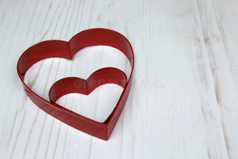 Two Red Heart Shaped cookie Cutter on wooden White back stock image Two Red Heart Shaped cookie Cutter on wooden White back stock image