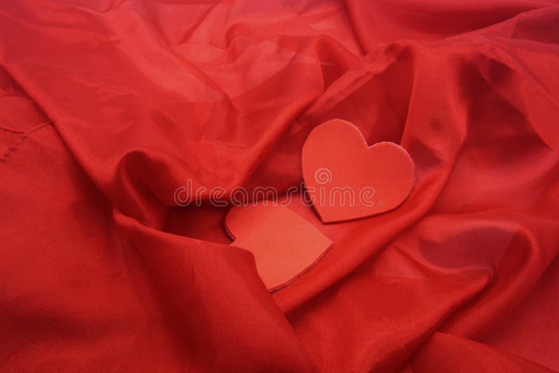 Two red hearts on red silk background with ripples