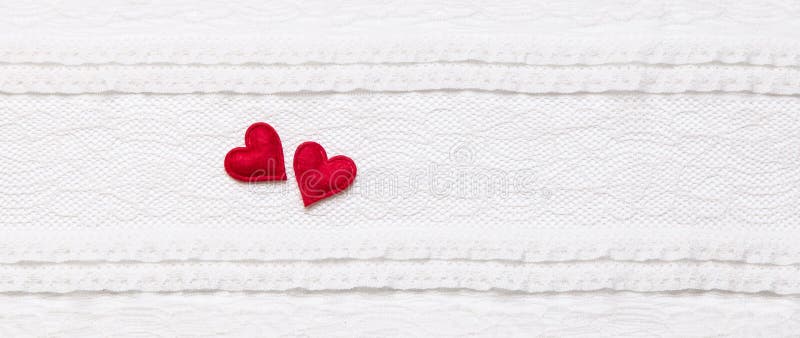 Two red hearts on white lace fabric