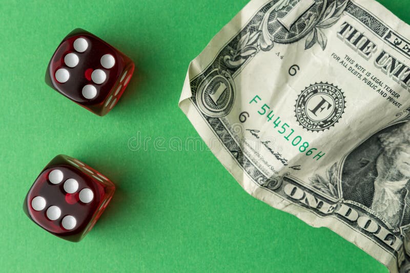 Two red playing dices with one dollar bill on green table. Luck and fortune concept