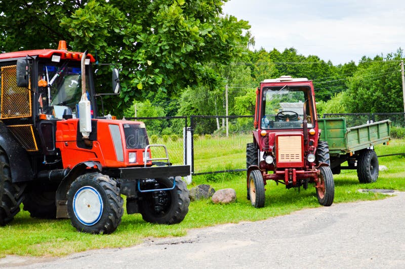 Two red professional agricultural construction tractor with large wheels with a tread for plowing the field, land, transportation stock photography Two red professional agricultural construction tractor with large wheels with a tread for plowing the field, land, transportation stock photography