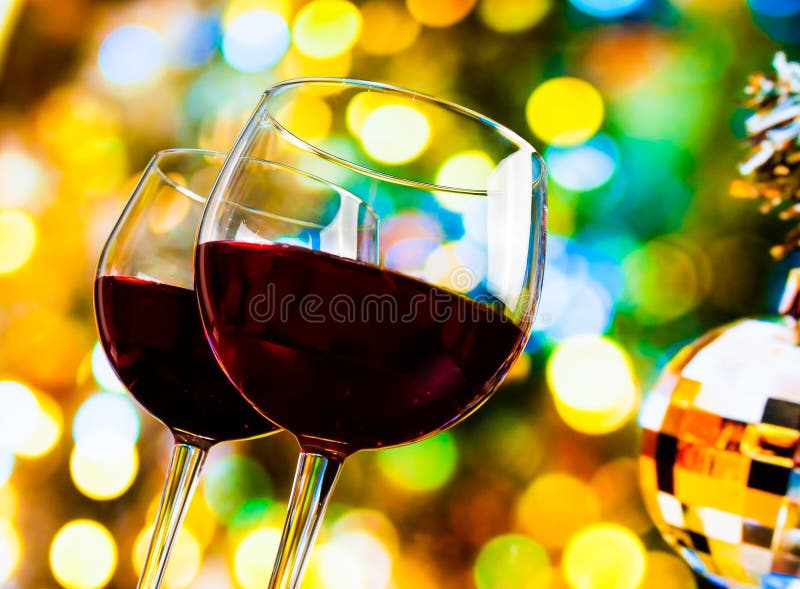 Two red wine glasses against colorful bokeh lights and sparkling disco ball background, festive and fun concept