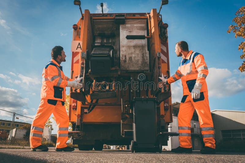 Two refuse collection workers loading garbage into waste truck royalty free stock images Two refuse collection workers loading garbage into waste truck royalty free stock images