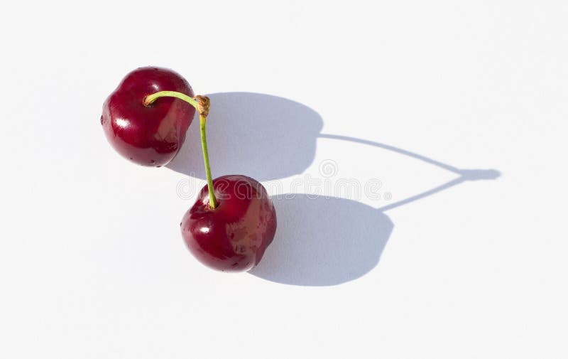 Two ripe cherries on the white background