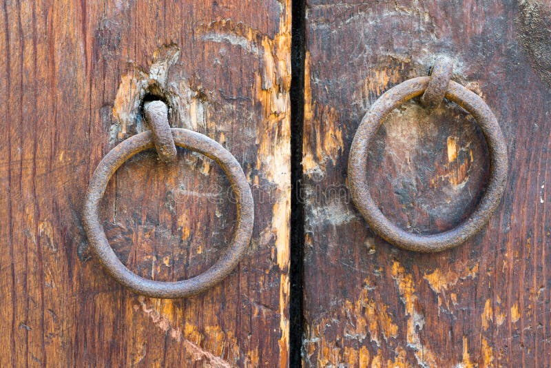 Two rusty iron ring door knobs over an old wooden door