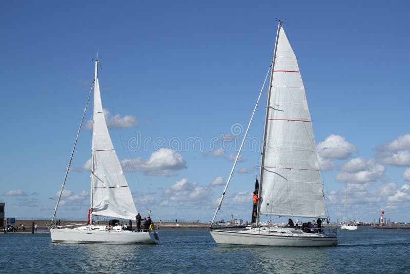 Two sailboats closeup in the marina in holland with a blue sky with clouds