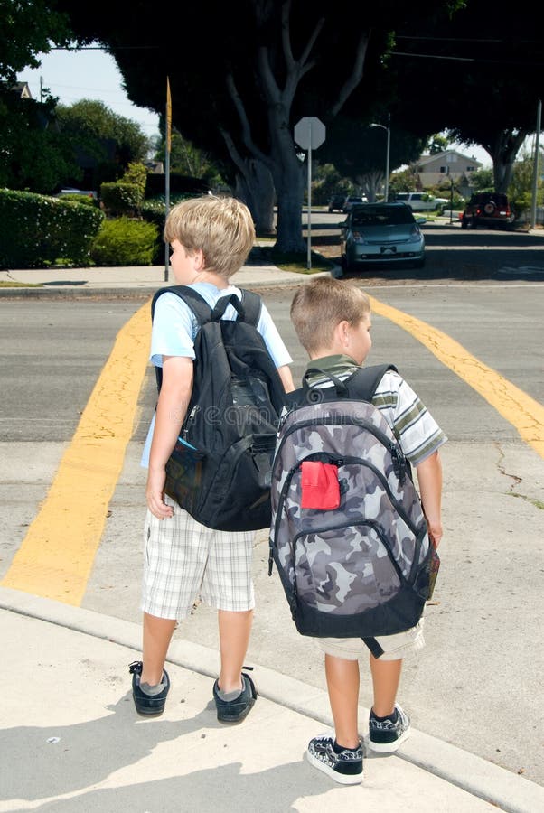 Due bambini in attesa a una croce piedi mentre erano sulla strada per la scuola a guardare il traffico.