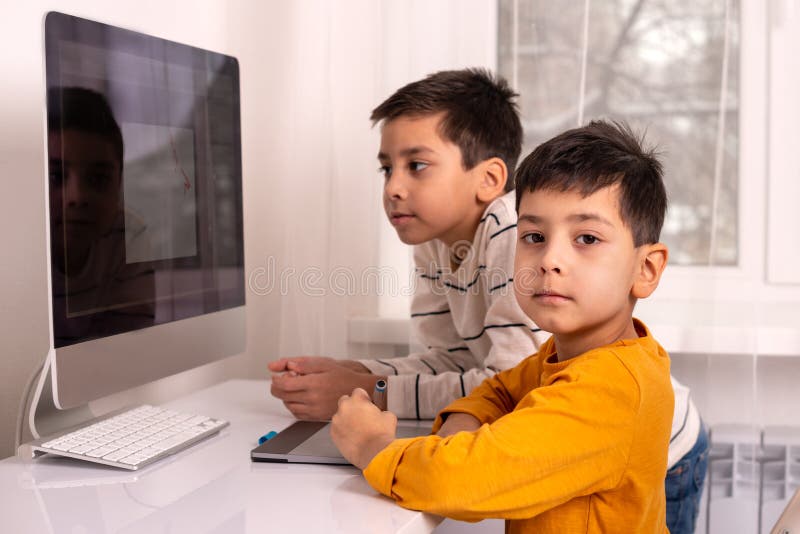 Two schoolboys boys doing their homework with a computer. stock photo Two schoolboys boys doing their homework with a computer. stock photo