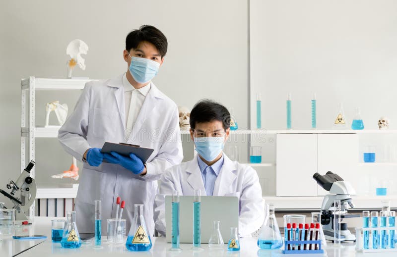 Two scientists with face mask and gown working in laboratory. Omicron strain testing process, Coronavirus disease 2019 stock image