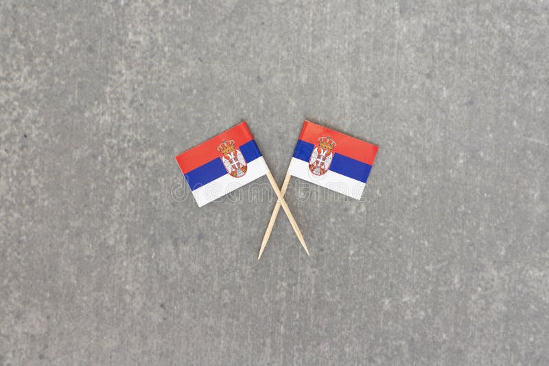 Two Serbian Flags on Crossed Toothpicks with Grey Stone Background stock photo