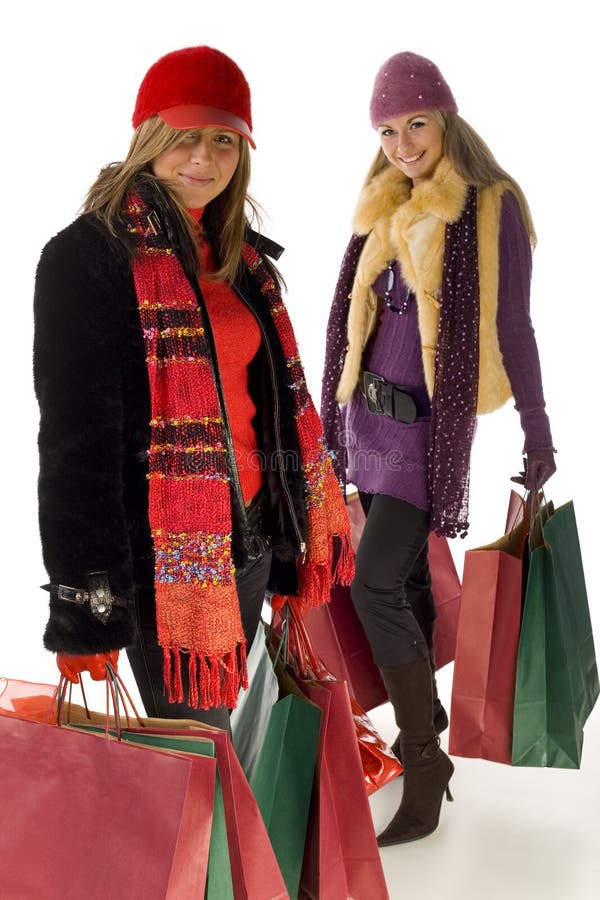 Two young women with shopping bags. They're smiling and looking at camera. Front view. Two young women with shopping bags. They're smiling and looking at camera. Front view.