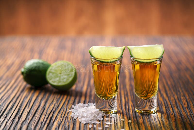 Two shot of gold tequila on a brown wooden background ,selectiv