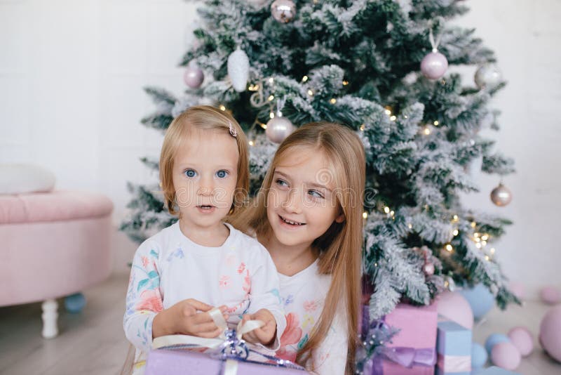 Two sisters at home with Christmas tree and presents. Happy children girls with Christmas gift boxes and decorations. royalty free stock images Two sisters at home with Christmas tree and presents. Happy children girls with Christmas gift boxes and decorations. royalty free stock images