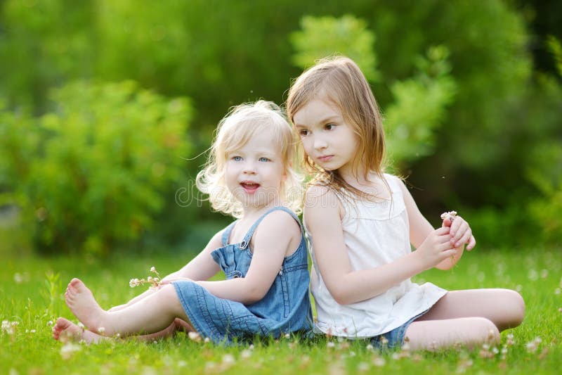 Two Sisters Sitting on the Grass on Summer Day Stock Photo - Image of ...