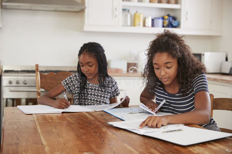 Two Sisters Sitting at Table in Kitchen Doing Homework Stock Image ...