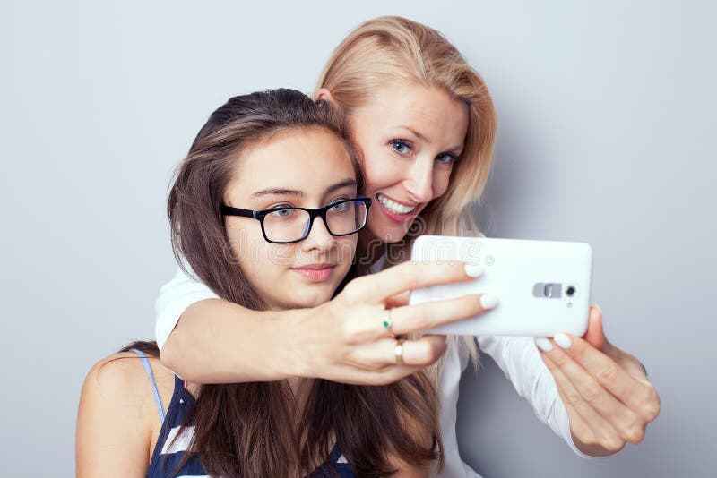 Two sisters using smart phone for selfie. 