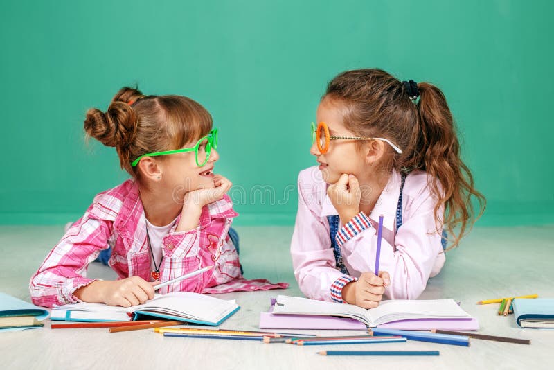 Two small girls speak and teach homework. The concept of childhood, learning, friendship, family, school, lifestyle. stock photography Two small girls speak and teach homework. The concept of childhood, learning, friendship, family, school, lifestyle. stock photography
