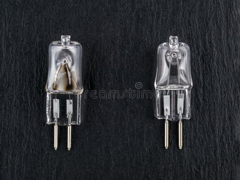 Two small halogen bulbs on a black background: one new and one burned out. gx6. 35 bipin bulb for pilot light of photo studio royalty free stock images